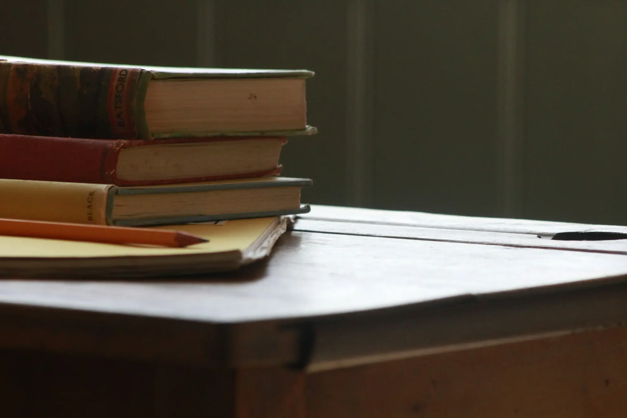 Libros y lápiz sobre una mesa de madera de despacho