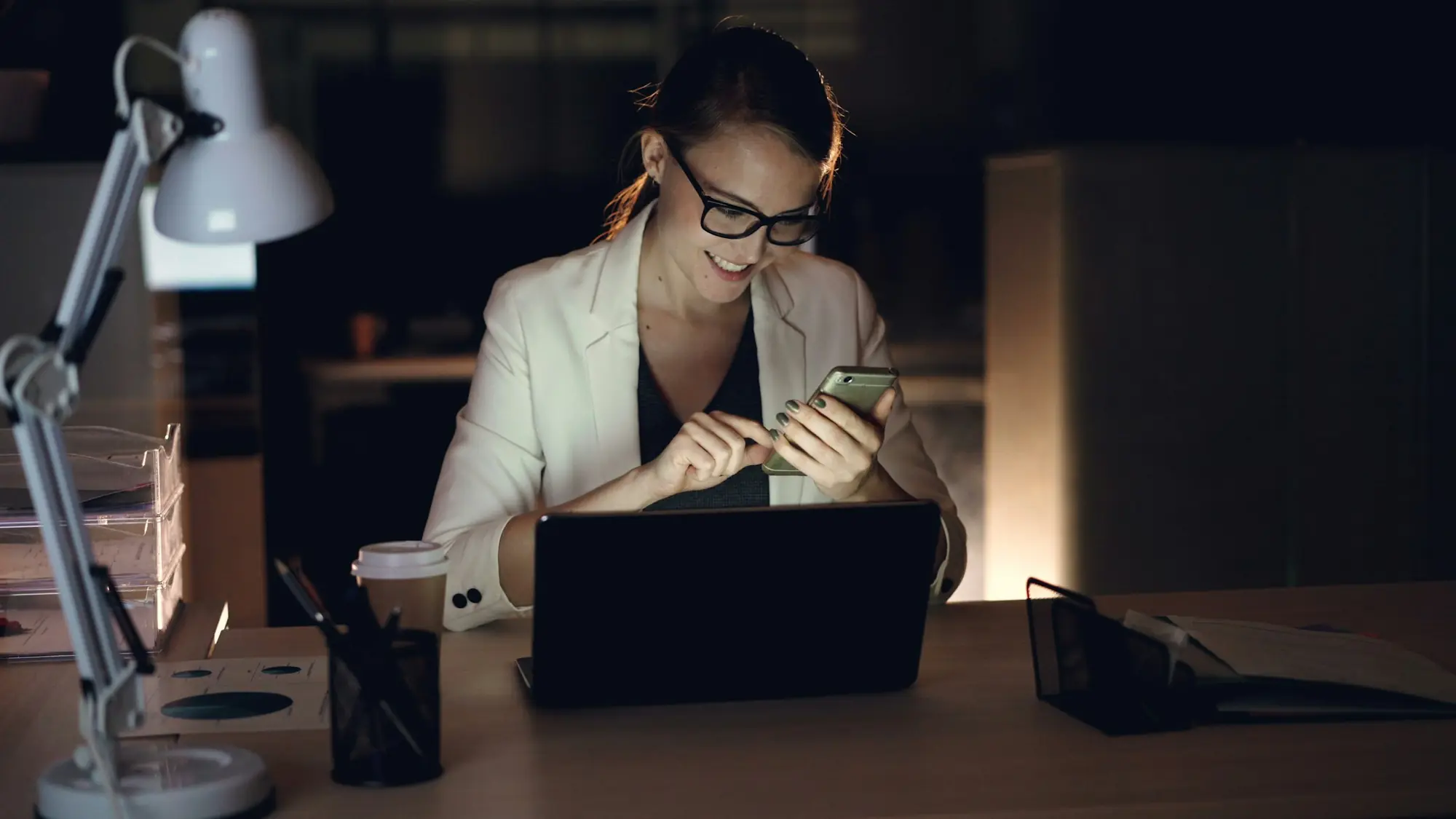 Profesional trabajando con su portátil en la oficina al anochecer